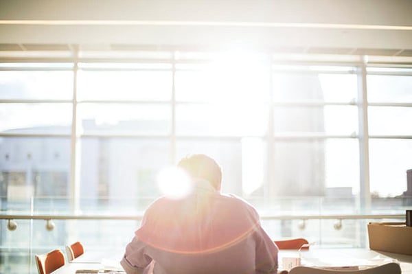 A man sat down at a desk in a sun filled room pondering the question - 'what is full stack automation?'